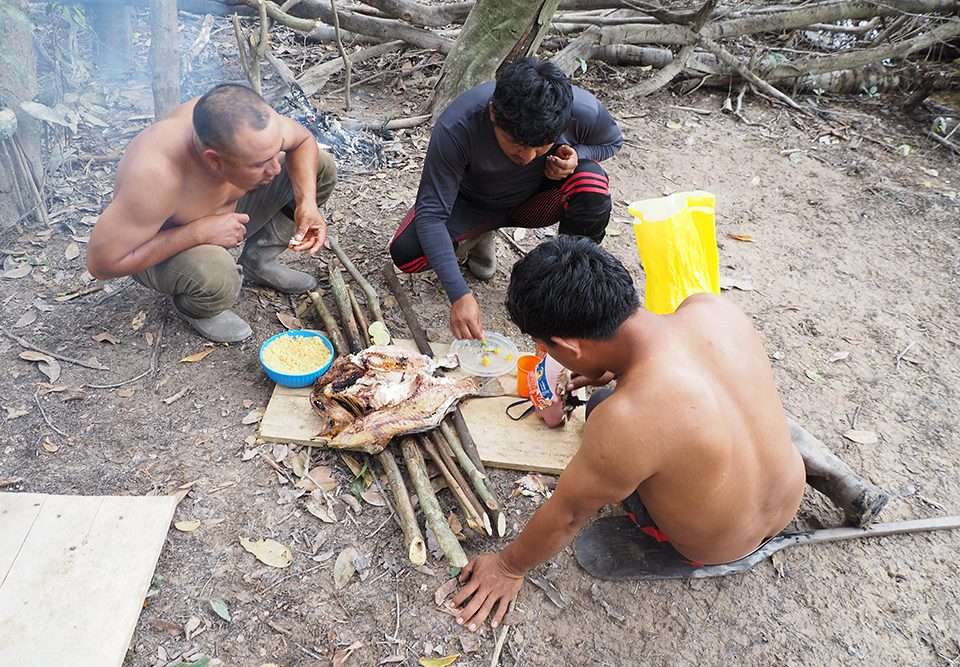 3 Wai Wai share a meal of peacock bass and farine in the forest